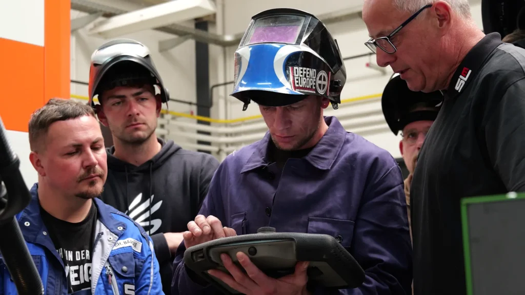SLM Welding School Trains the Next Generation with Cobot Welding 2 a group of welding students looking at a teach pendant